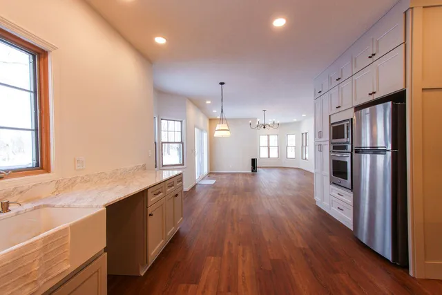 a large kitchen with cabinets wooden floor and stainless steel appliances