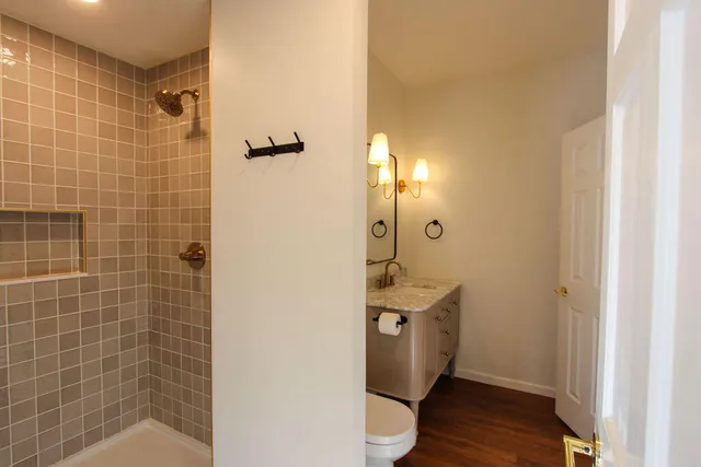 a bathroom with a double vanity sink a toilet and shower