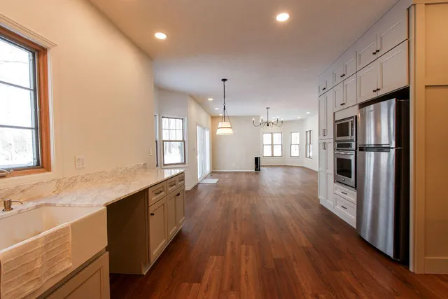 a large kitchen with a center island wooden floor stainless steel appliances and windows