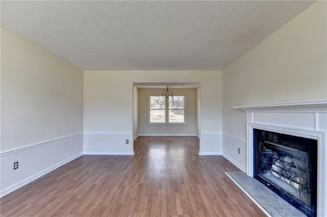 an empty room with wooden floor fireplace and windows