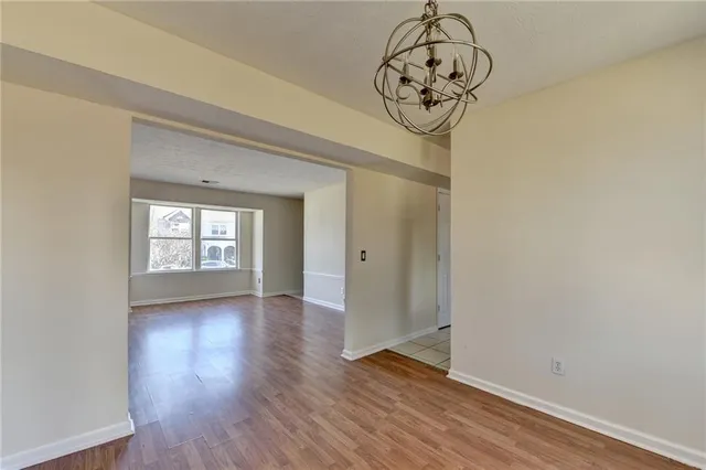 a view of a hallway with wooden floor and a chandelier