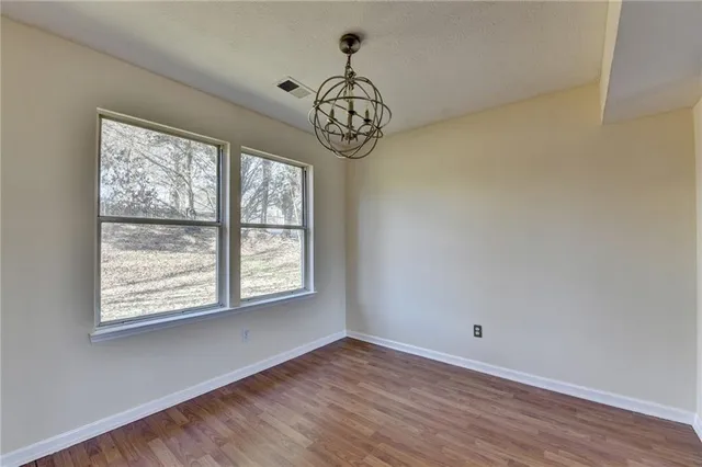 a view of an empty room with window and wooden floor