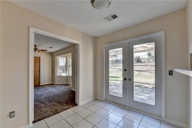 a view of an empty room with window and cabinet area