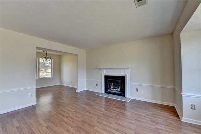 an empty room with wooden floor a fireplace and windows
