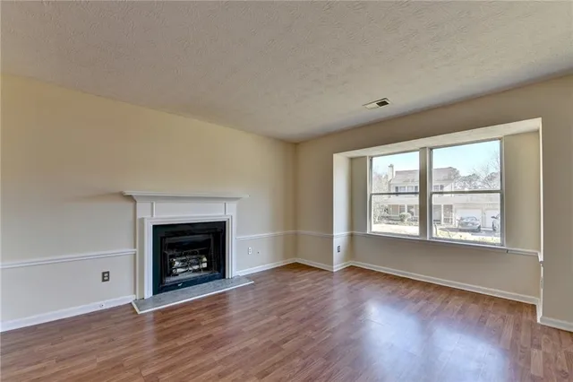 an empty room with wooden floor fireplace and windows