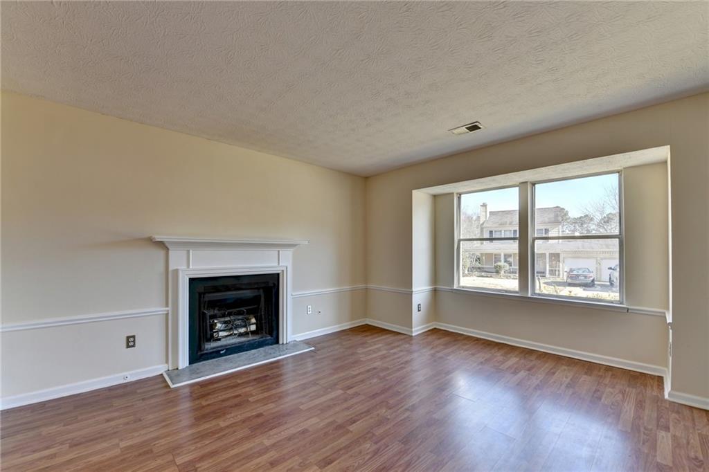2082 Montgomery Trail Duluth, GA 30096 - Photo 9 of 45 an empty room with wooden floor fireplace and windows