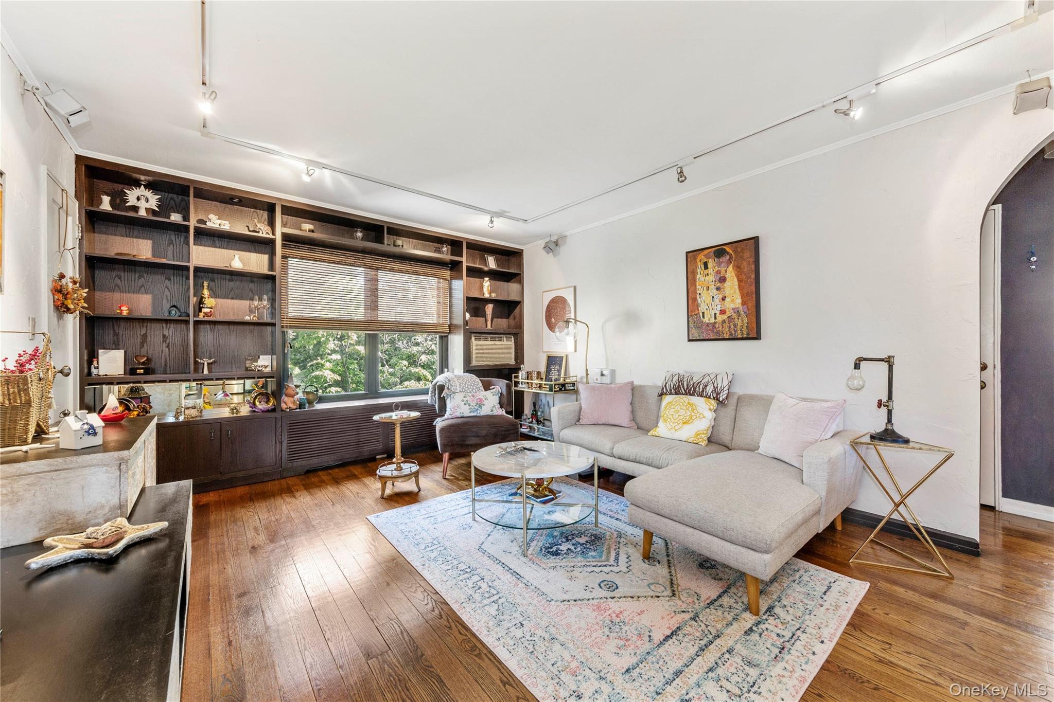 Living room featuring track lighting, arched walkways, and wood-type flooring