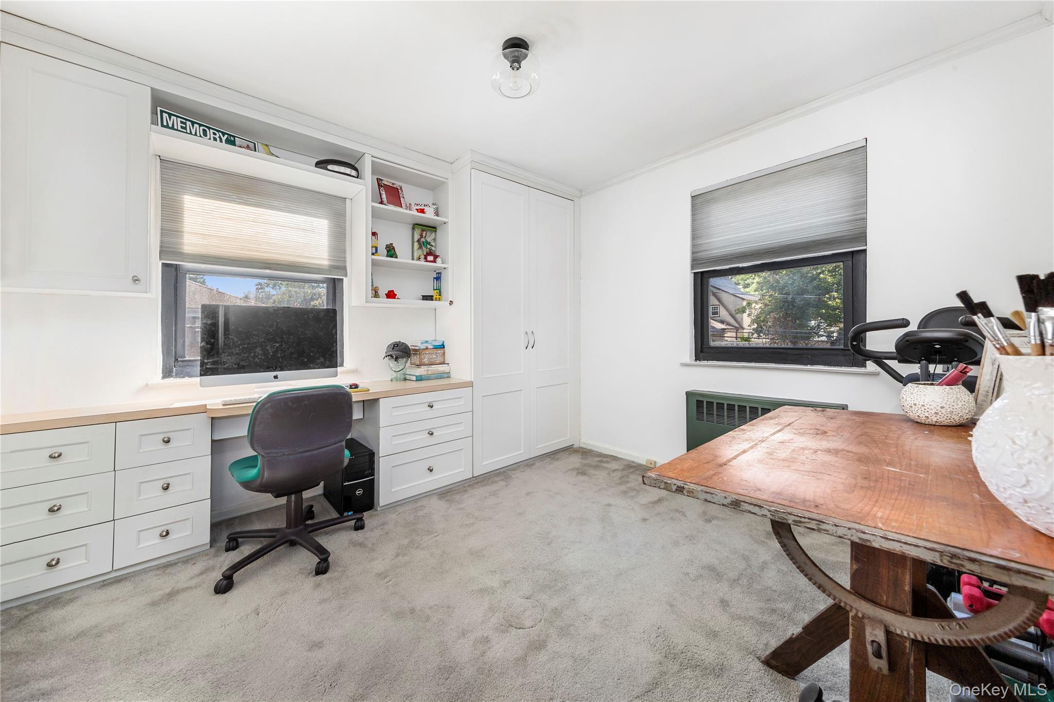 16 Terrace Circle, Unit 14C Great Neck, NY 11021 - Photo 5 of 9 Office area with built in study area, light carpet, radiator, and crown molding