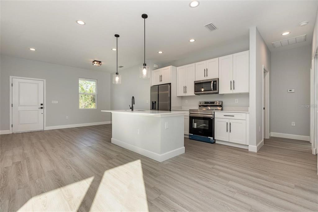 13451 Kaplan Terrace Port Charlotte, FL 33981 - Photo 6 of 27 a large kitchen with kitchen island a stove a sink a center island and wooden floor