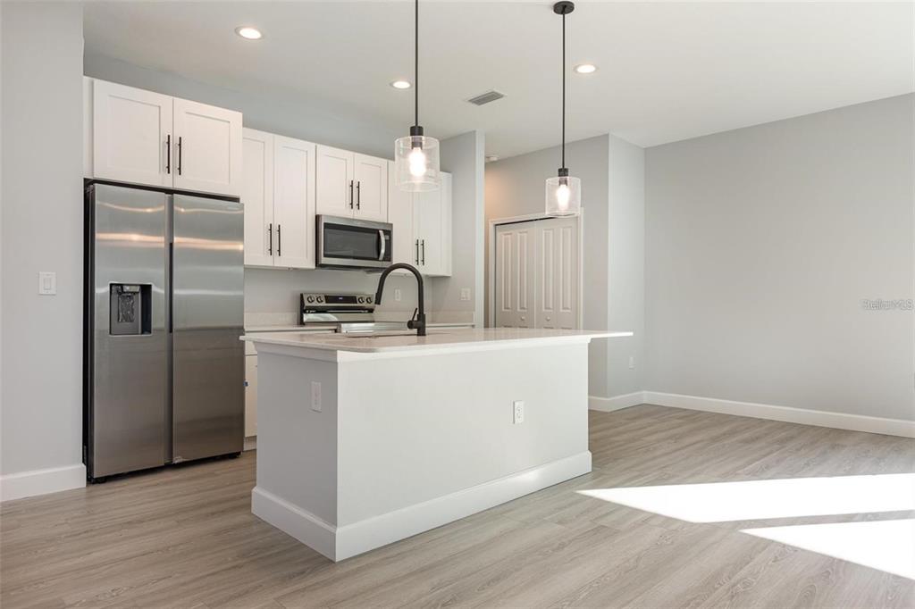 13451 Kaplan Terrace Port Charlotte, FL 33981 - Photo 7 of 27 a kitchen with kitchen island a counter top space wooden floor and a ceiling fan