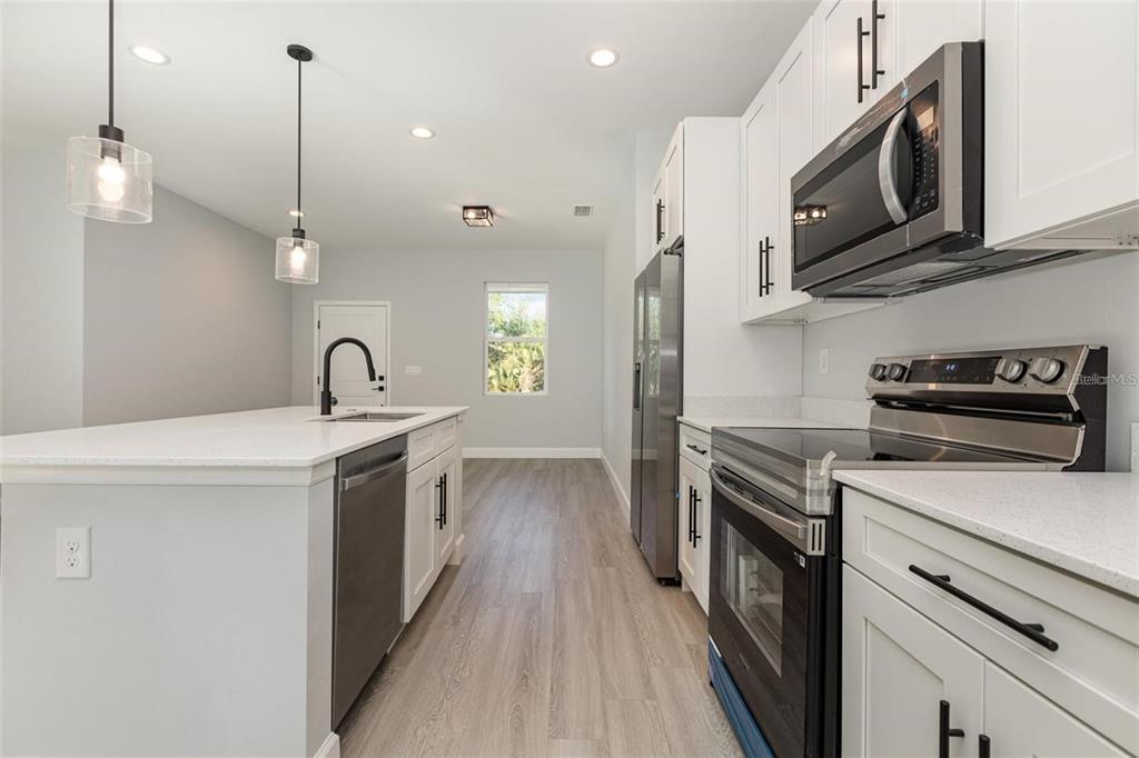 13451 Kaplan Terrace Port Charlotte, FL 33981 - Photo 8 of 27 a kitchen with stainless steel appliances granite countertop a sink a stove a microwave and wooden cabinets