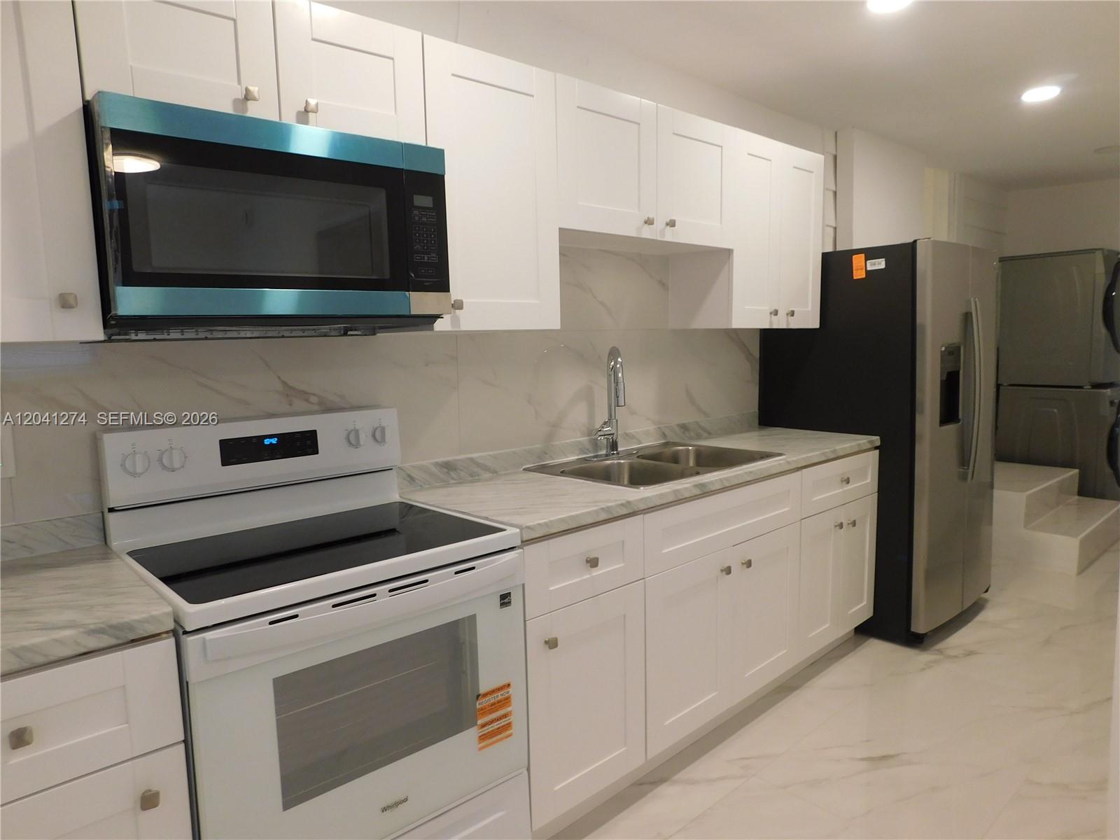 2230 Northwest 58th Street, Unit B Miami, FL 33142 - Photo 6 of 18 a kitchen with granite countertop white cabinets and stainless steel appliances