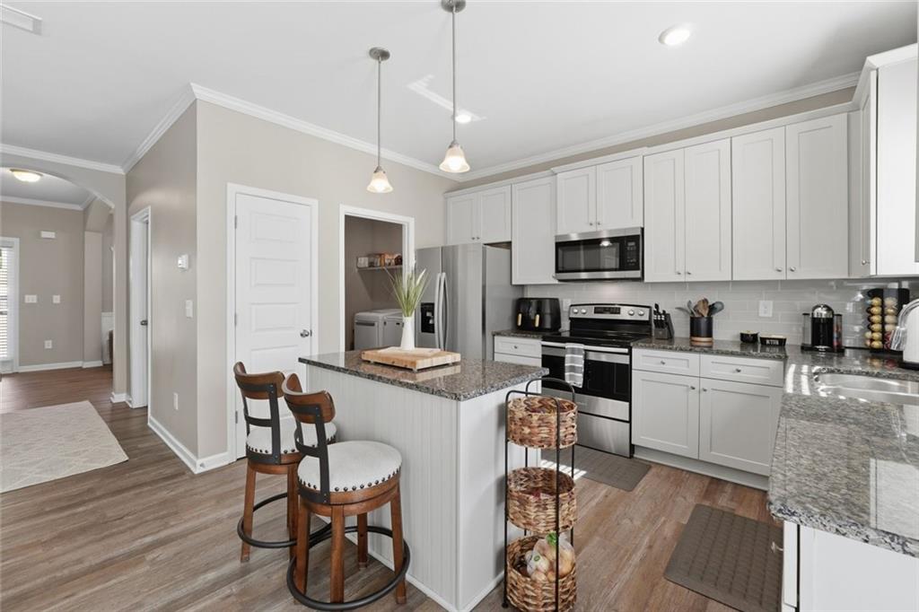 166 Ashbridge Lane Dallas, GA 30132 - Photo 8 of 35 a kitchen with stainless steel appliances granite countertop a stove top oven a sink a dining table and chairs with wooden floor