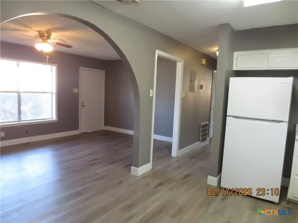a view of an empty room with wooden floor and a window
