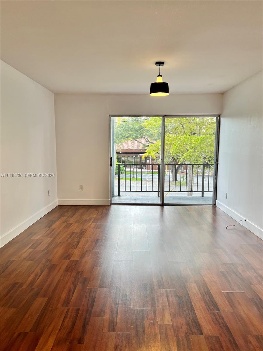 9225 Southwest 87th Avenue, Unit A8 Miami, FL 33176 - Photo 4 of 14 a view of an empty room with wooden floor and a window