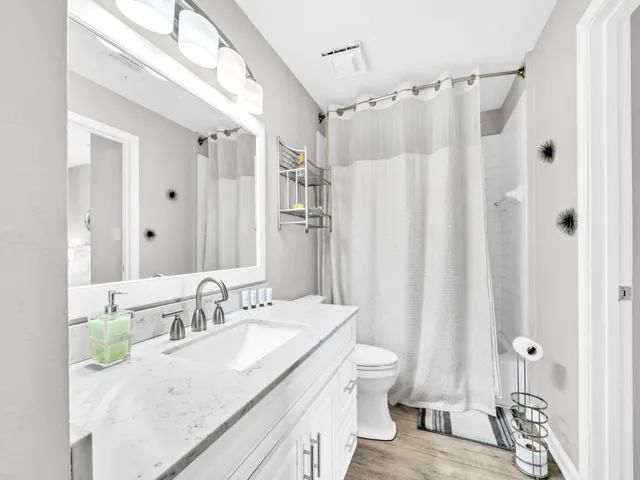 a bathroom with a granite countertop sink a toilet and shower curtain
