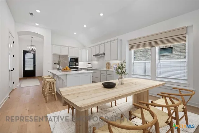 a kitchen with a table chairs refrigerator and cabinets