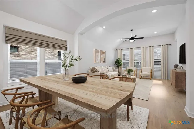 a view of a dining room and livingroom with furniture wooden floor a rug a flat screen tv a potted plant and a chandelier