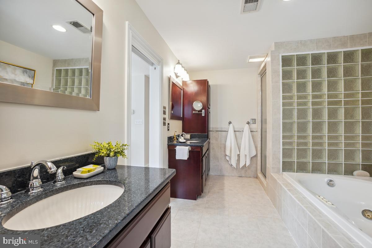 8610 Melwood Road Bethesda, MD 20817 - Photo 40 of 44 a bathroom with a granite countertop sink a bathtub and a mirror
