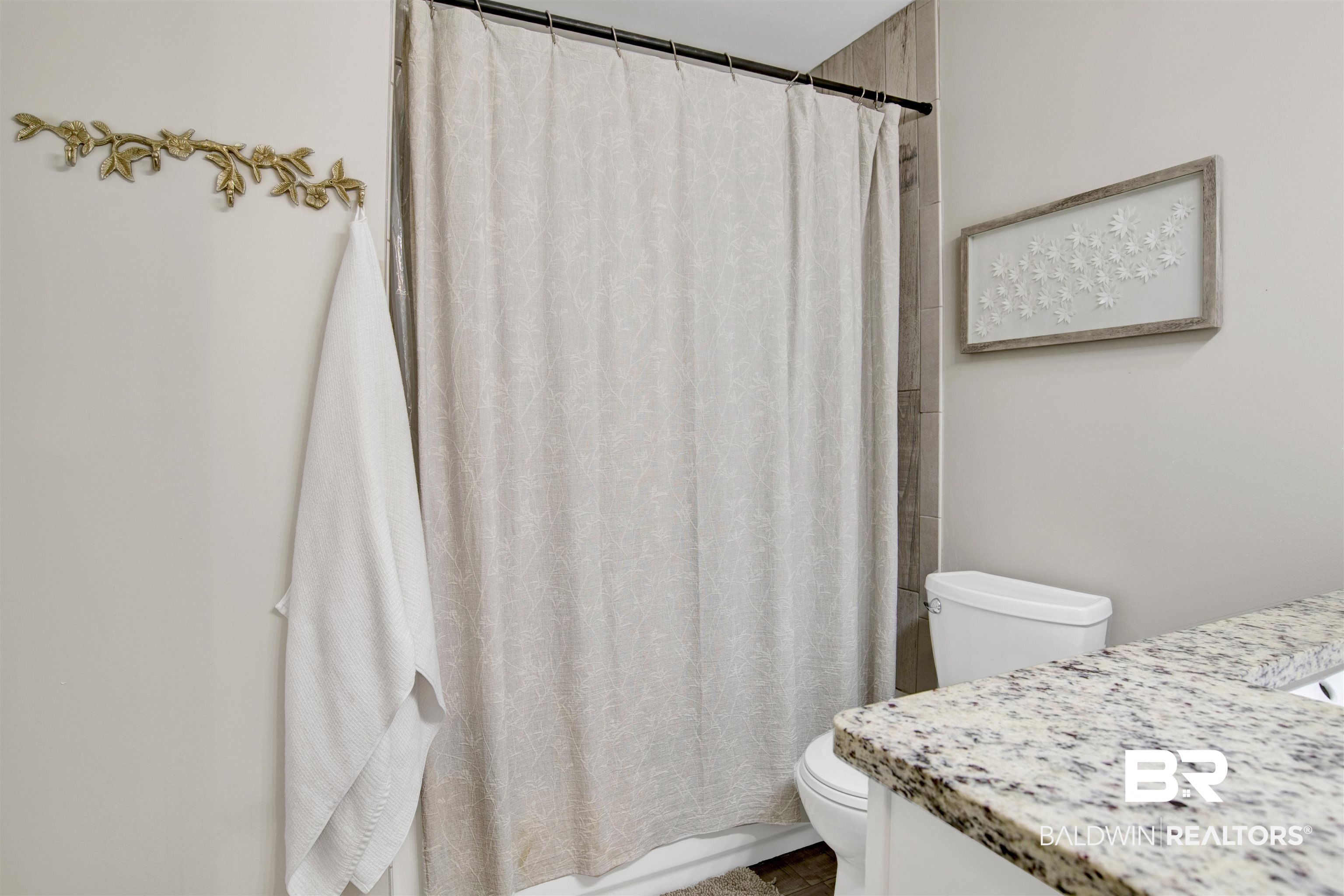 253 Maplewood Loop Daphne, AL 36526 - Photo 23 of 30 Bathroom featuring a shower with a neutral-toned curtain, wood-look wall paneling, and a toilet