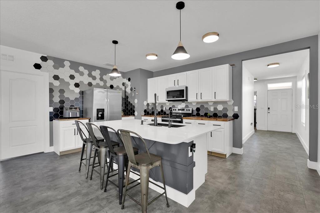 6763 Grace Hammock Road Harmony, FL 34773 - Photo 3 of 20 a kitchen with stainless steel appliances kitchen island granite countertop a dining table chairs and white cabinets