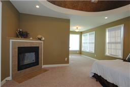 Beautiful mastersuite with fireplace, sitting area and contoured ceiling over the bedroom