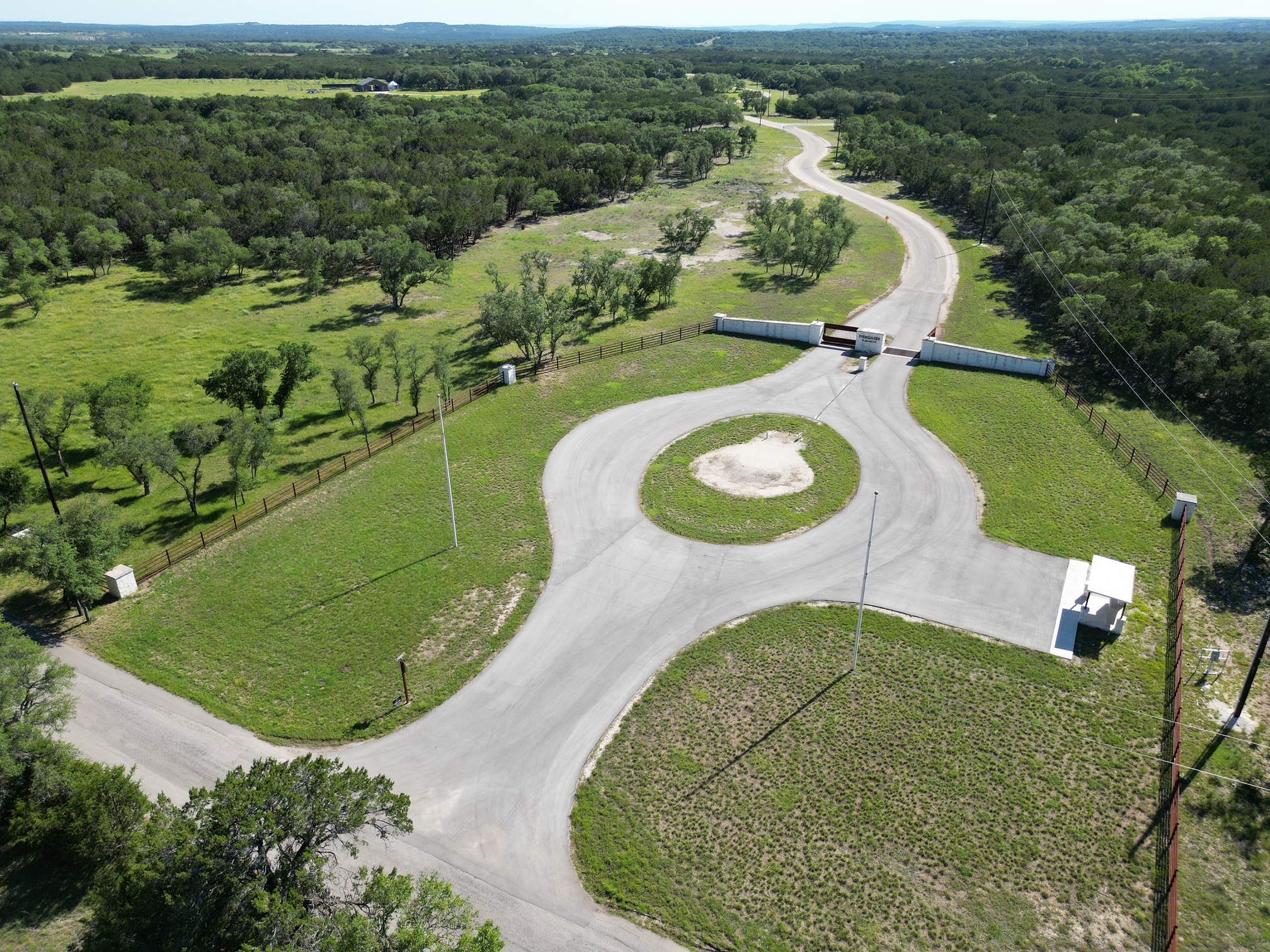 0 Cr 104 Road Lampasas, TX 76550 - Photo 16 of 18 Gated community entrance featuring stone walls, a circular driveway, and extensive natural landscaping