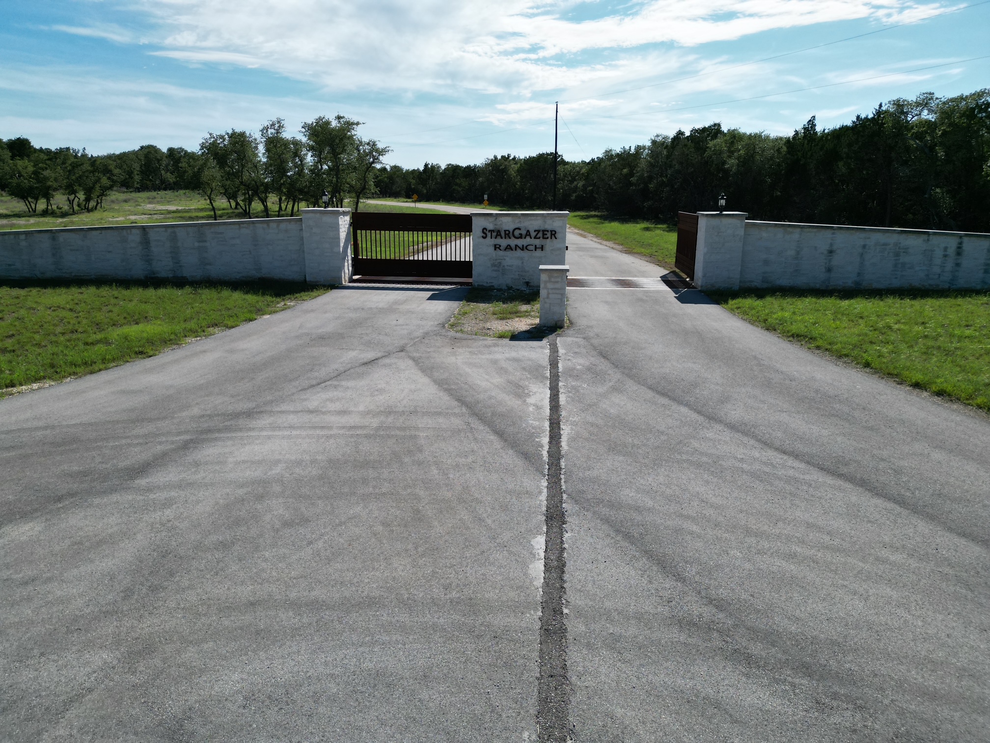 0 Cr 104 Road Lampasas, TX 76550 - Photo 18 of 18 Asphalt driveway leading to a stone wall entry with a metal gate and property signage