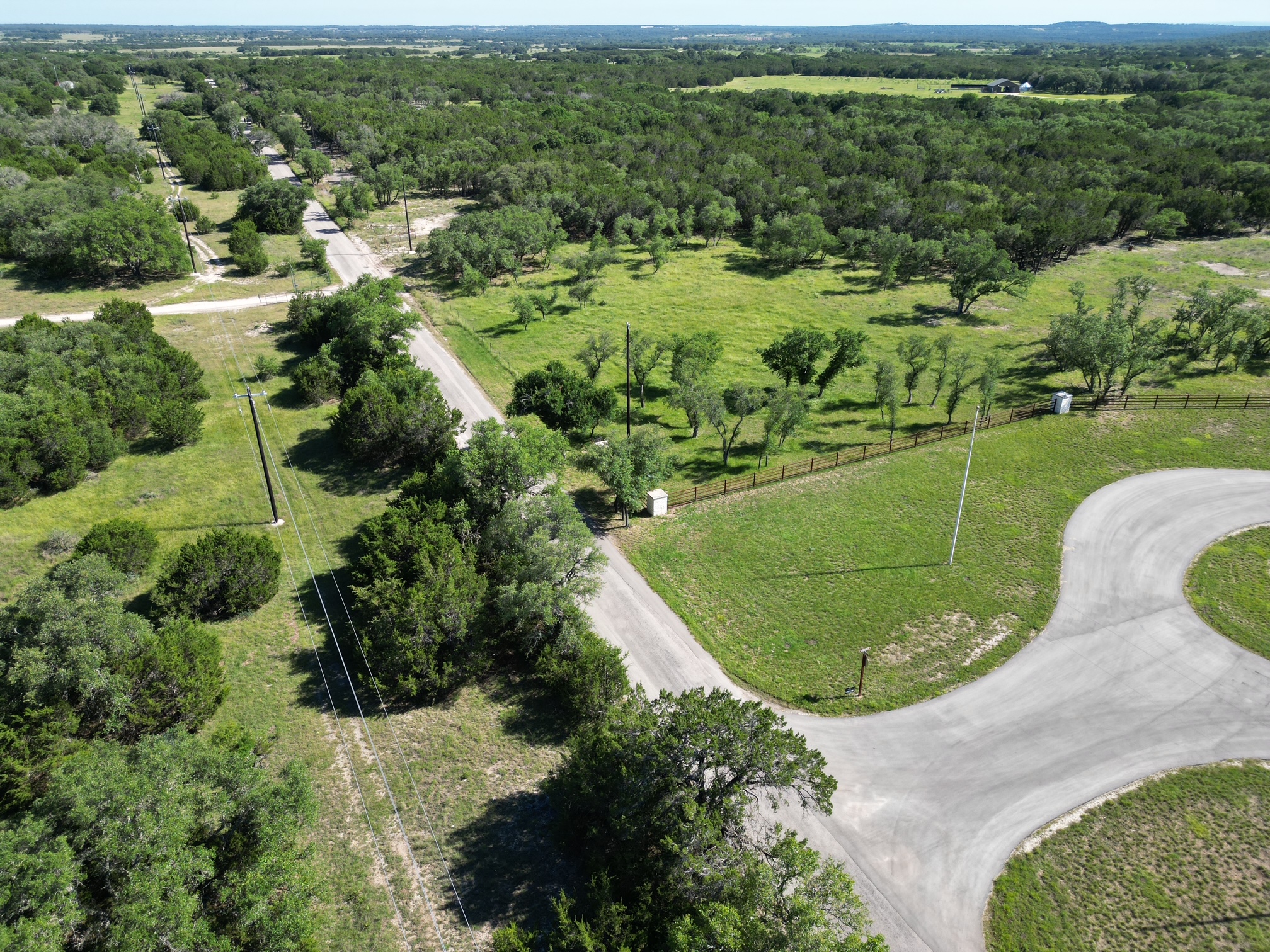 0 Cr 104 Road Lampasas, TX 76550 - Photo 4 of 18 Aerial landscaping featuring extensive tree coverage, open grassy areas, a paved cul-de-sac, and a dirt road