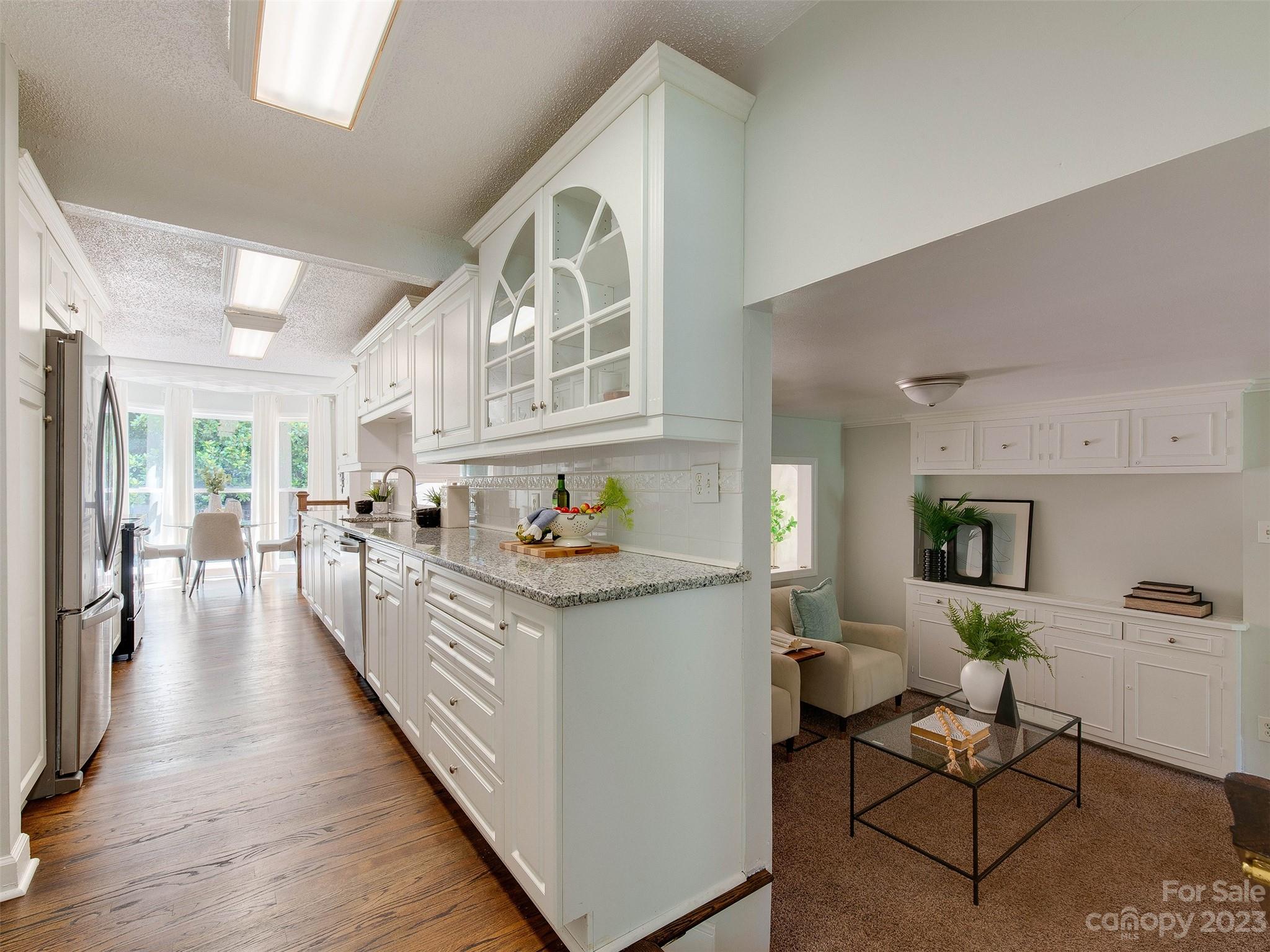 2916 Goneaway Road Charlotte, NC 28210 - Photo 24 of 48 a kitchen with stainless steel appliances granite countertop a stove top oven a sink a dining table and chairs with wooden floor
