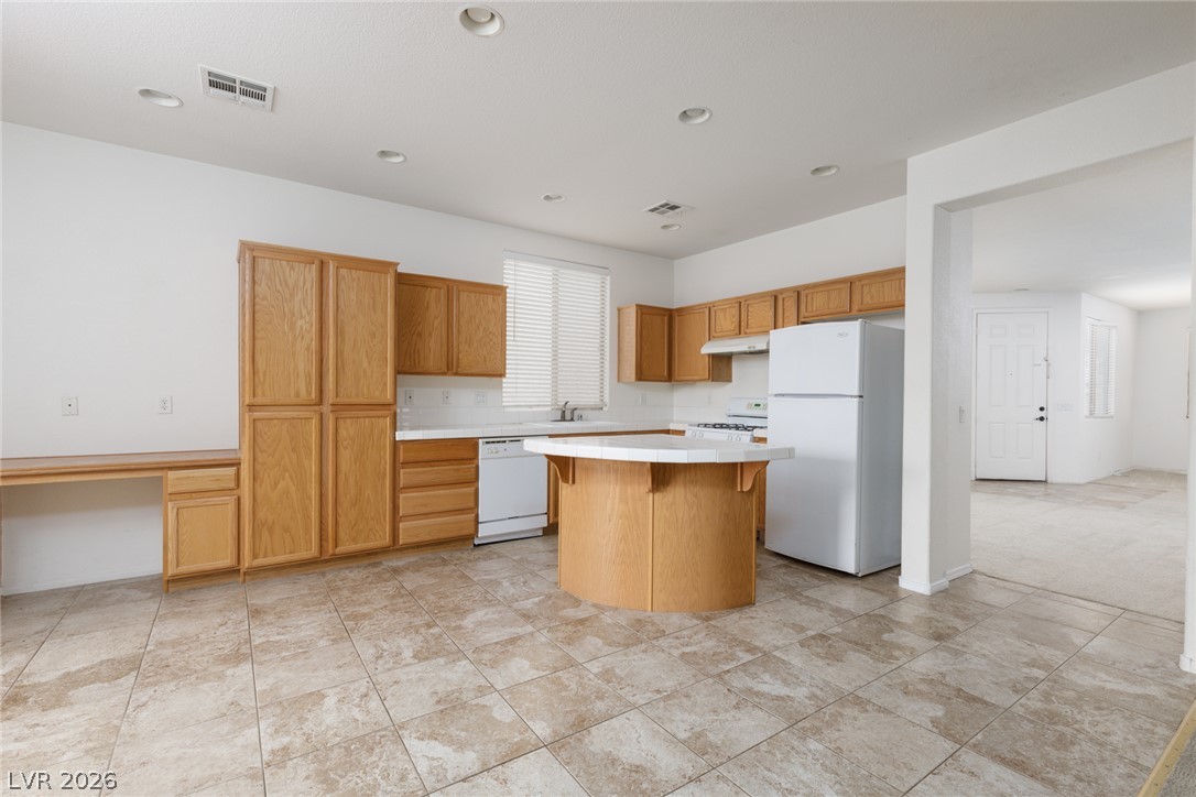 787 Rise Canyon Drive Henderson, NV 89052 - Photo 4 of 22 A functional kitchen features light wood cabinetry, a practical island, and durable tile flooring.