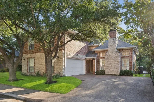 a front view of a house with a garden and trees