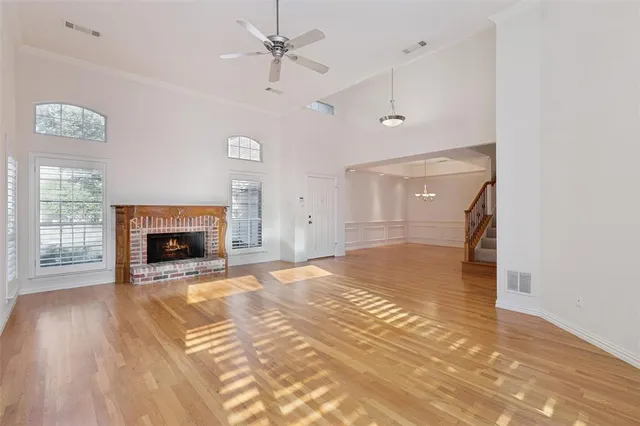a view of a livingroom with a fireplace a ceiling fan and wooden floor