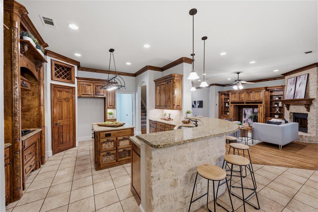 620 Highview Lane Hurst, TX 76054 - Photo 4 of 40 Open-concept kitchen featuring an island with built-in storage, granite countertops, tile flooring, and custom cabinetry with crown molding