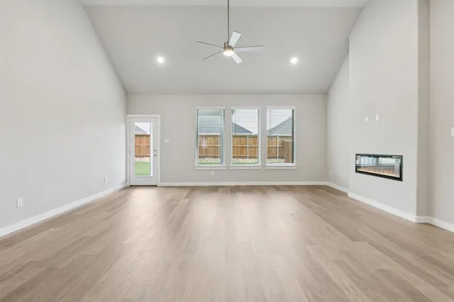 an empty room with wooden floor chandelier and windows