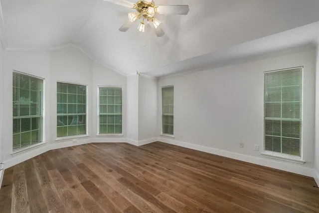 a view of an empty room with a window and wooden floor