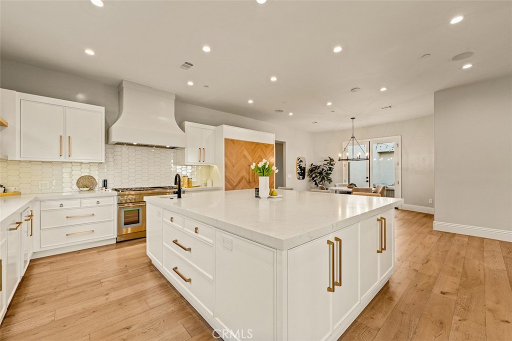 13248 Nightsky Drive Camarillo, CA 93012 - Photo 13 of 53 a large white kitchen with kitchen island a stove a sink a refrigerator and white cabinets with wooden floor