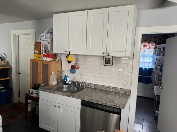 a kitchen with white cabinets and sink
