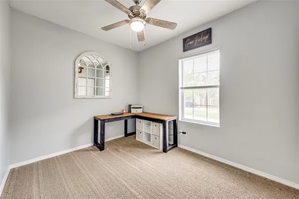 an empty room with windows and fan