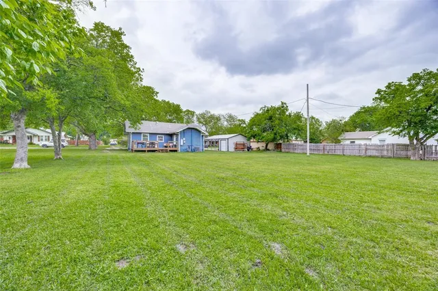 a view of a green field with house in the background