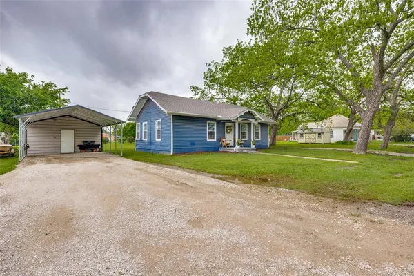 a front view of a house with a yard and trees
