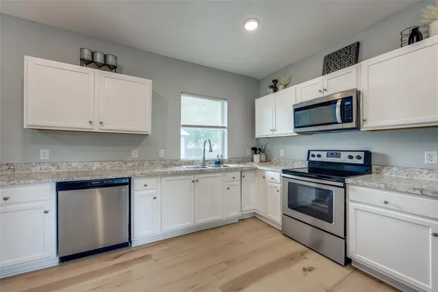 a kitchen with granite countertop wooden cabinets stainless steel appliances and a sink