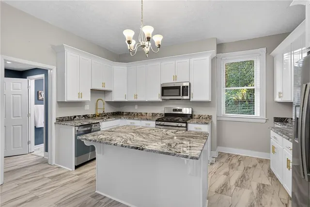 a kitchen with stainless steel appliances granite countertop a stove top oven a sink dishwasher a refrigerator and white cabinets with wooden floor