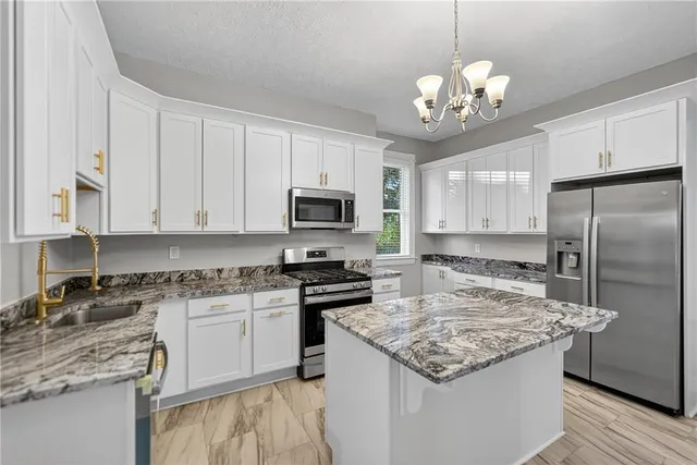 a kitchen with kitchen island granite countertop stainless steel appliances a sink stove and refrigerator