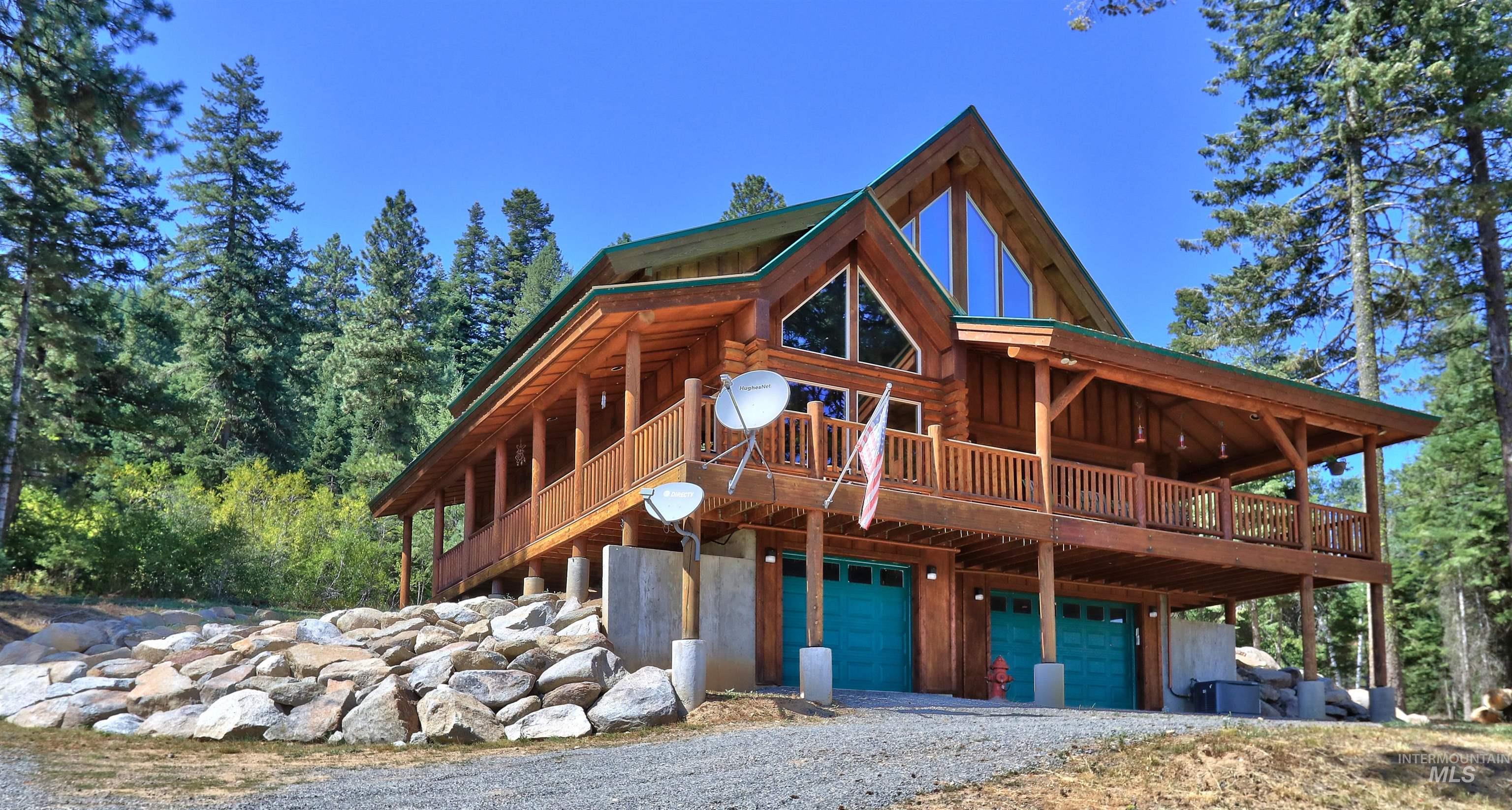 1539 West Mountain Road Cascade, ID 83611 - Photo 6 of 33 View of front of home featuring a wooden deck, an attached garage, gravel driveway, and log exterior