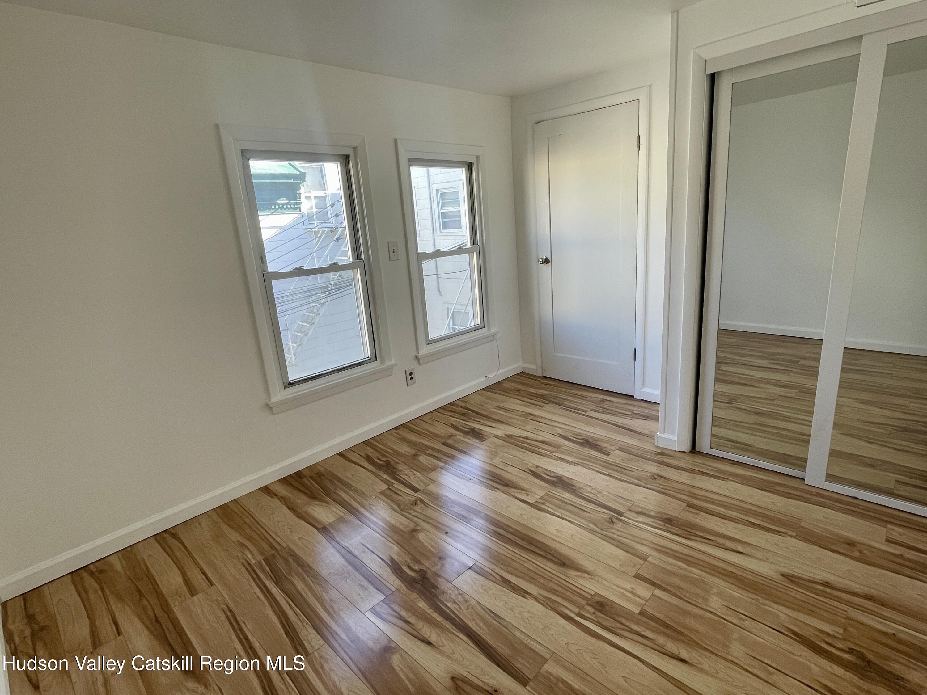 720 Warren Street, Unit 7 Hudson, NY 12534 - Photo 3 of 10 an empty room with wooden floor and windows