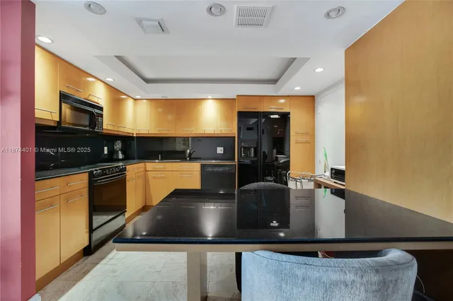 a kitchen with kitchen island granite countertop a sink a counter top space cabinets and stainless steel appliances