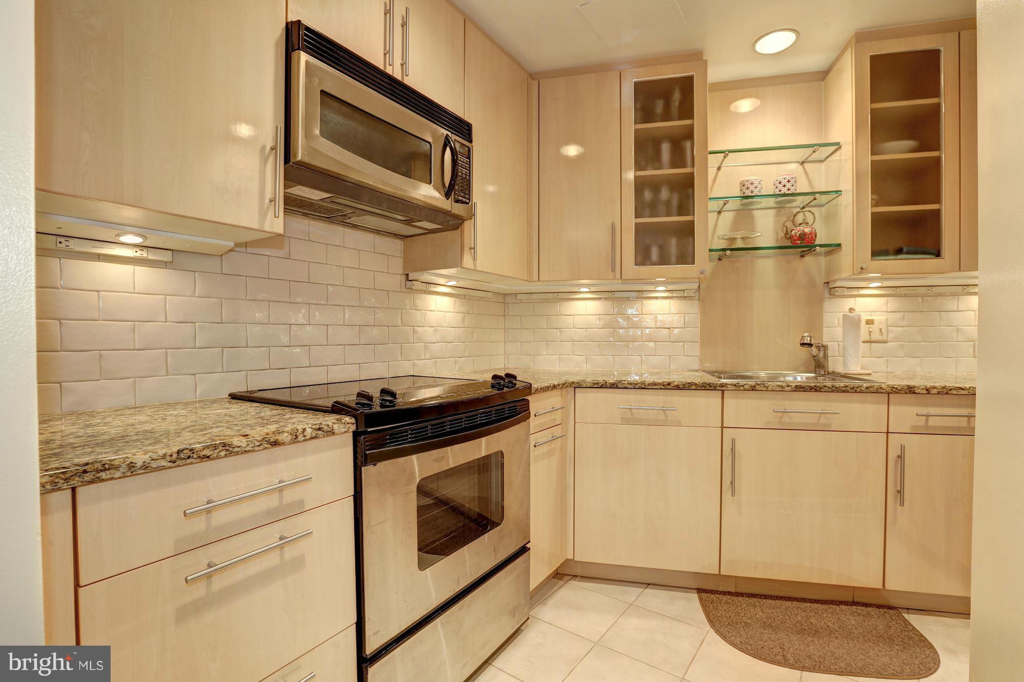 3 Washington Circle Northwest, Unit 103 Washington, DC 20037 - Photo 8 of 28 a kitchen with granite countertop a stove a sink and white cabinets