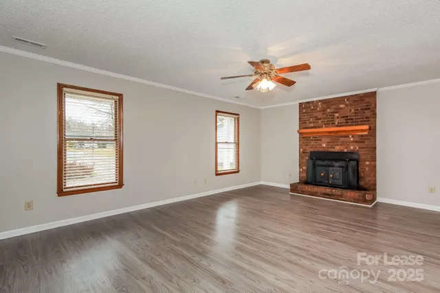 a view of an empty room with chandelier fan and wooden floor