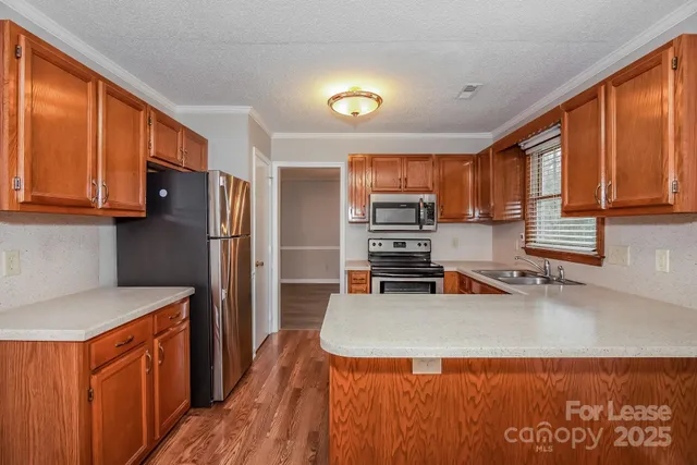 a kitchen with stainless steel appliances granite countertop a refrigerator a stove and a sink